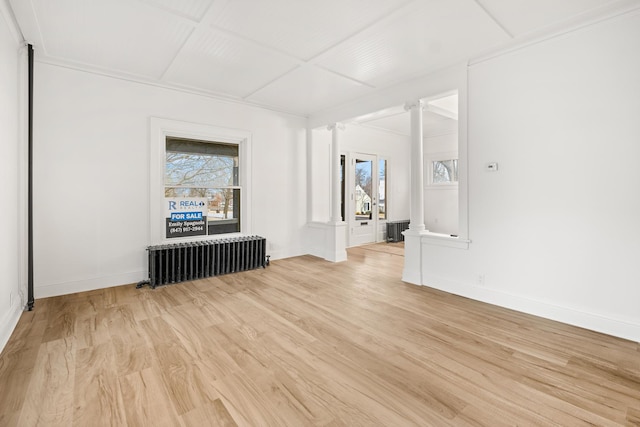 spare room featuring radiator, light hardwood / wood-style floors, and decorative columns