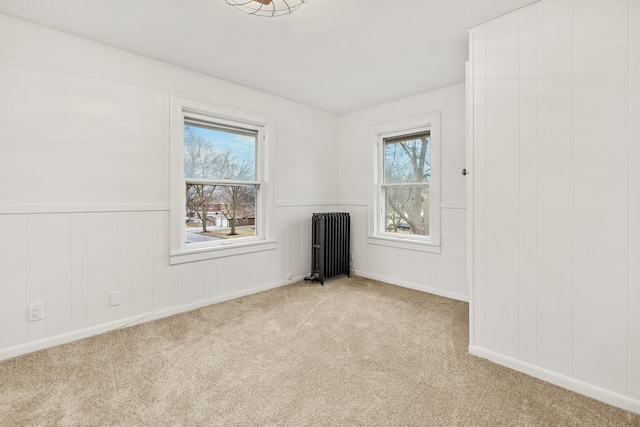 unfurnished room with radiator and light colored carpet