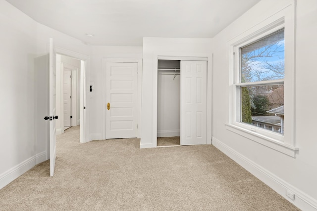 unfurnished bedroom with light colored carpet and a closet