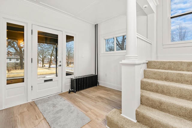 entryway with hardwood / wood-style floors, ornamental molding, and radiator heating unit