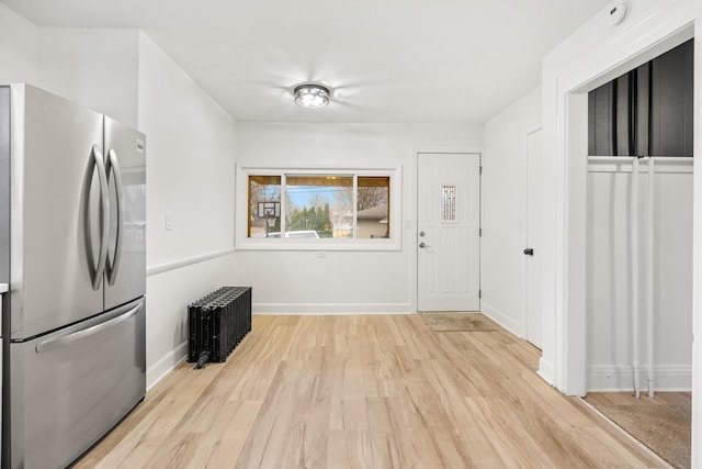 kitchen with stainless steel refrigerator, radiator, and light hardwood / wood-style floors