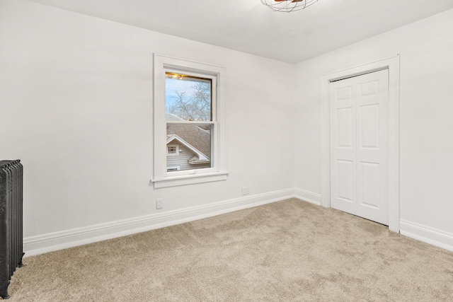 spare room featuring light colored carpet and radiator