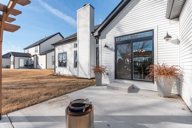 view of exterior entry with a patio area and a lawn