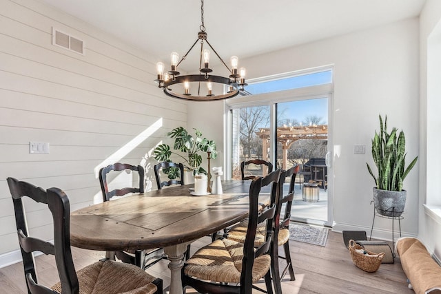 dining area featuring hardwood / wood-style floors, a notable chandelier, and wooden walls