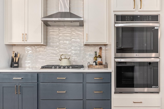 kitchen with white cabinetry, appliances with stainless steel finishes, wall chimney range hood, and decorative backsplash