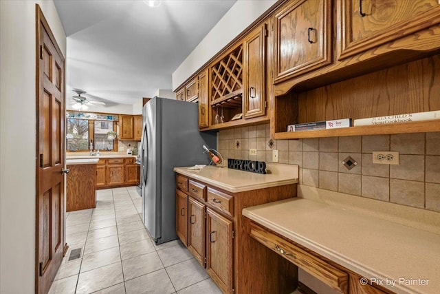 kitchen featuring stainless steel refrigerator, ceiling fan, decorative backsplash, and light tile patterned floors