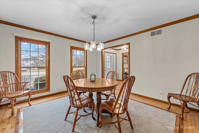 dining room featuring an inviting chandelier, ornamental molding, and light hardwood / wood-style floors