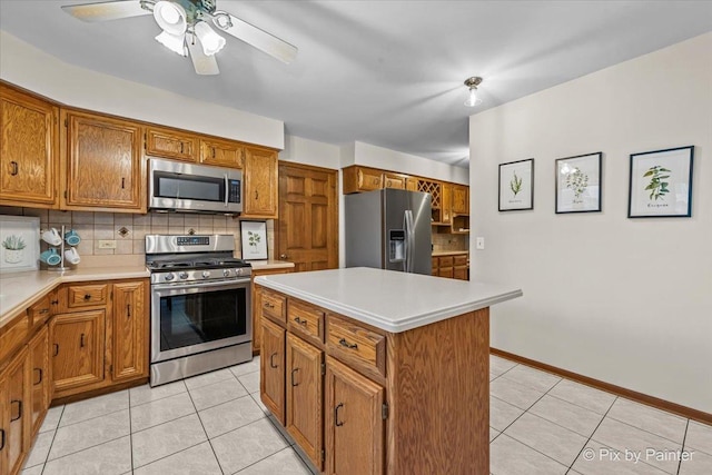 kitchen featuring stainless steel appliances, a kitchen island, light tile patterned floors, and backsplash