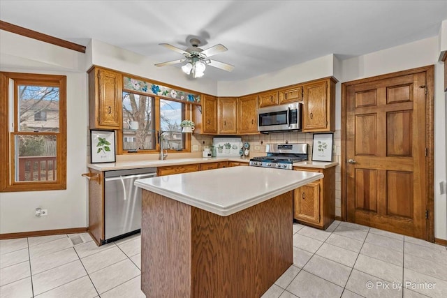 kitchen with sink, appliances with stainless steel finishes, backsplash, a center island, and light tile patterned flooring