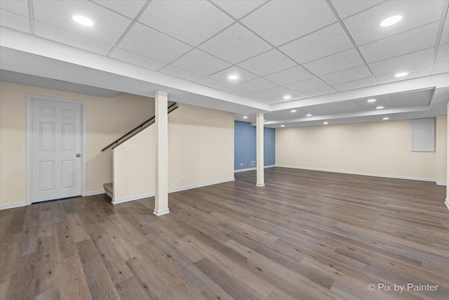 basement featuring a drop ceiling and wood-type flooring