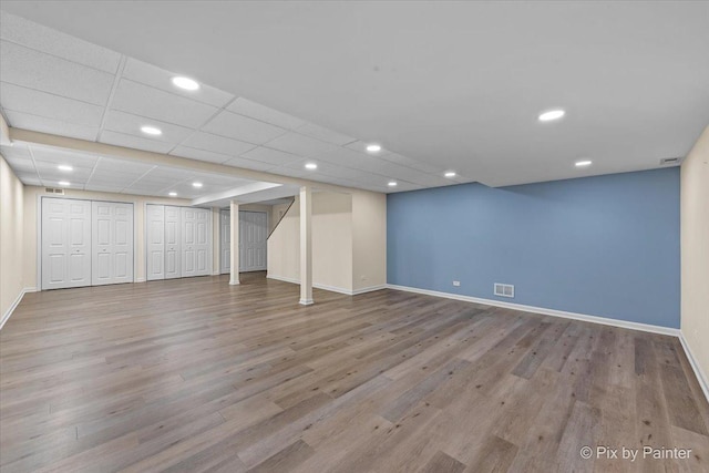 basement with light hardwood / wood-style flooring and a drop ceiling