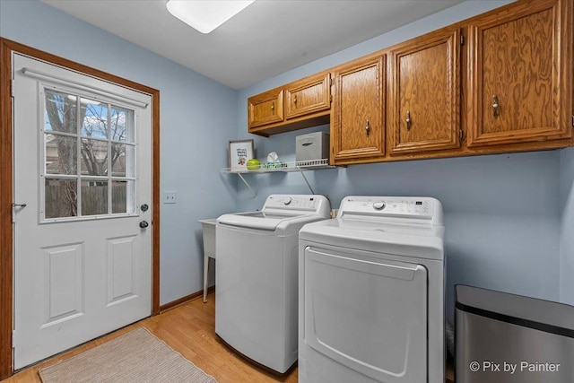 laundry area featuring independent washer and dryer, cabinets, and light hardwood / wood-style flooring