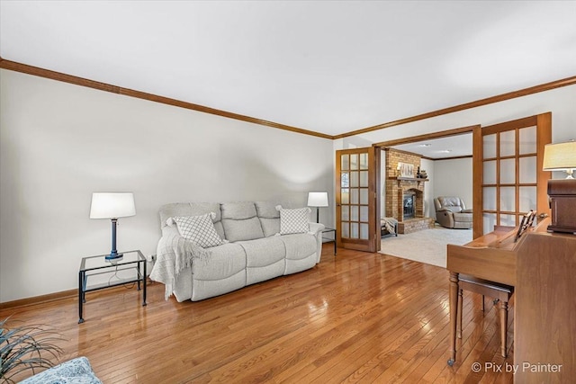 living room with french doors, crown molding, light wood-type flooring, a fireplace, and a baseboard heating unit