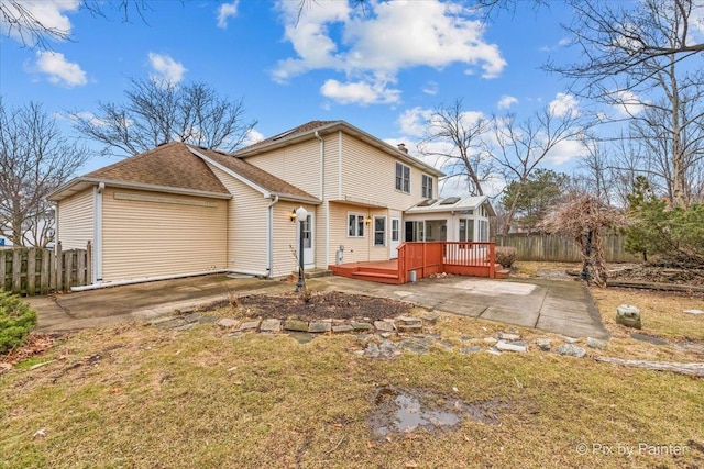 back of property featuring a wooden deck and a lawn