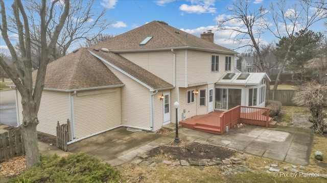 back of property with a wooden deck, a sunroom, and a patio area