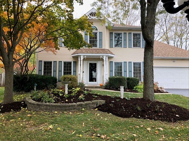 colonial inspired home featuring a garage and a front yard