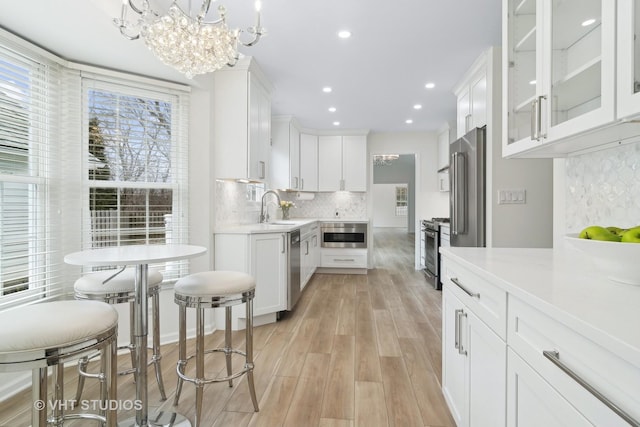 kitchen with white cabinetry, appliances with stainless steel finishes, sink, and pendant lighting