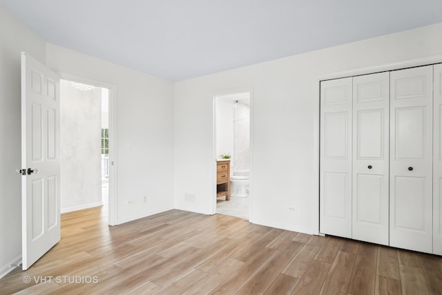 unfurnished bedroom featuring connected bathroom, light wood-type flooring, and a closet