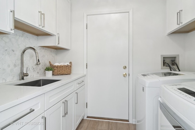 washroom featuring cabinets, sink, light hardwood / wood-style flooring, and washing machine and clothes dryer