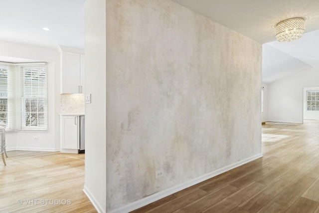 empty room featuring lofted ceiling, light hardwood / wood-style floors, and a chandelier