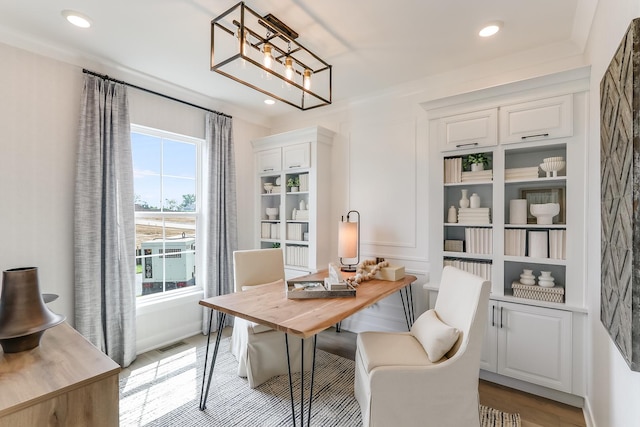 office space featuring built in features, an inviting chandelier, and light hardwood / wood-style flooring