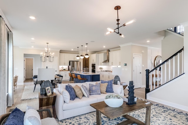 living room featuring ornamental molding, sink, a notable chandelier, and light hardwood / wood-style floors