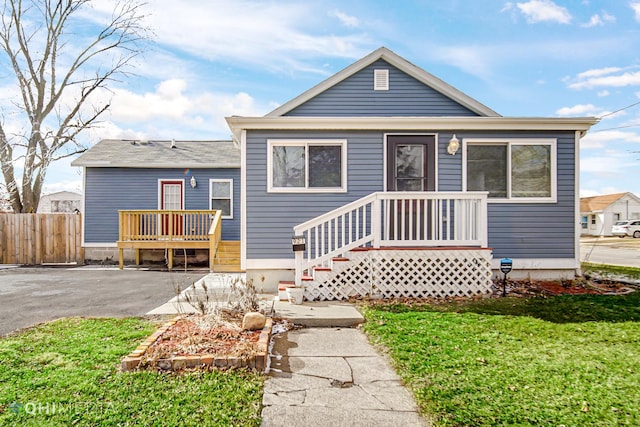 bungalow-style home with fence, driveway, and a front lawn