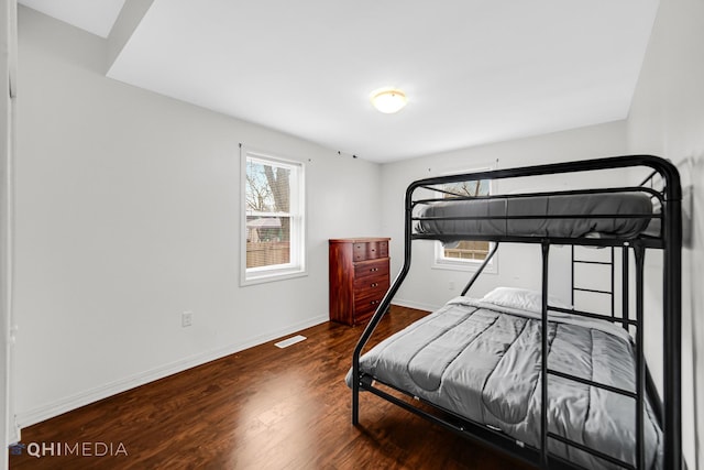 bedroom featuring visible vents, baseboards, and wood finished floors