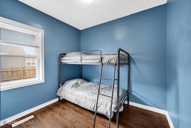 bedroom with visible vents, baseboards, and wood finished floors