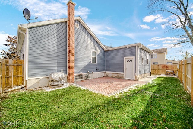 back of house with a patio area, a fenced backyard, a chimney, and a yard