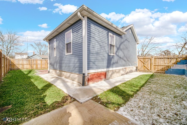 view of home's exterior with a lawn, a fenced backyard, and a gate