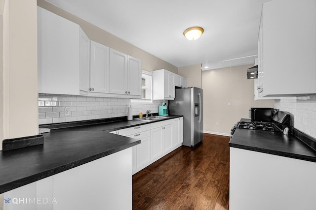 kitchen with a sink, dark countertops, black gas range, and stainless steel fridge with ice dispenser