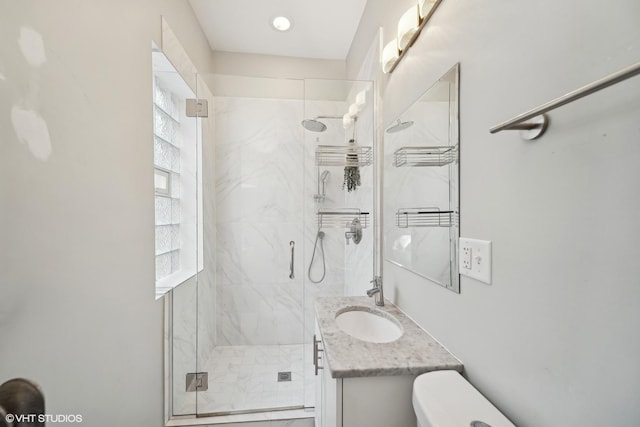 bathroom with vanity, toilet, and a shower with shower door