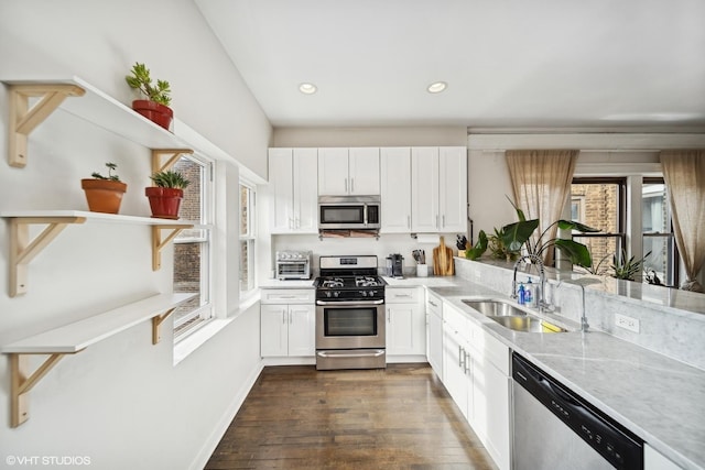 kitchen featuring sink, white cabinetry, light stone counters, dark hardwood / wood-style floors, and stainless steel appliances