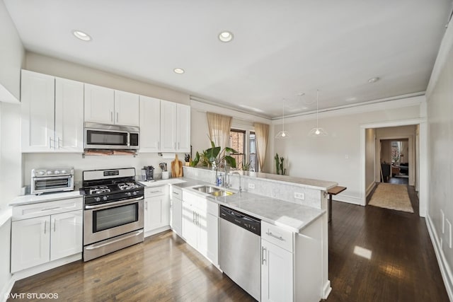 kitchen with white cabinetry, appliances with stainless steel finishes, sink, and kitchen peninsula