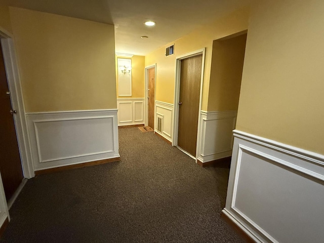 hall with dark colored carpet