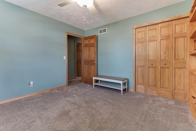 unfurnished bedroom featuring ceiling fan, a closet, carpet flooring, and a textured ceiling