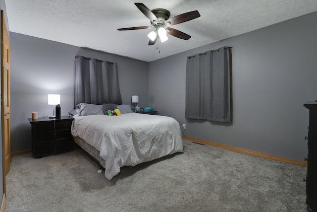 carpeted bedroom featuring ceiling fan and a textured ceiling