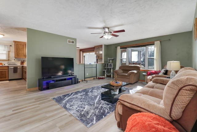 living room with ceiling fan, a textured ceiling, and light wood-type flooring