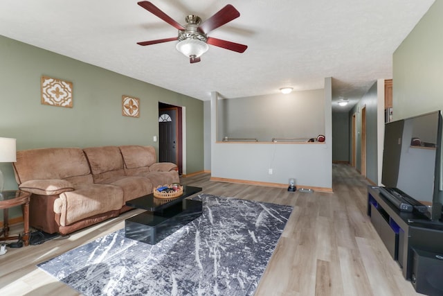 living room featuring ceiling fan, light hardwood / wood-style floors, and a textured ceiling