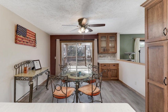 dining space featuring ceiling fan, plenty of natural light, a textured ceiling, and light wood-type flooring