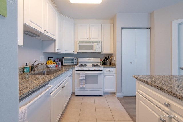 kitchen with stone counters, white cabinetry, sink, and white appliances