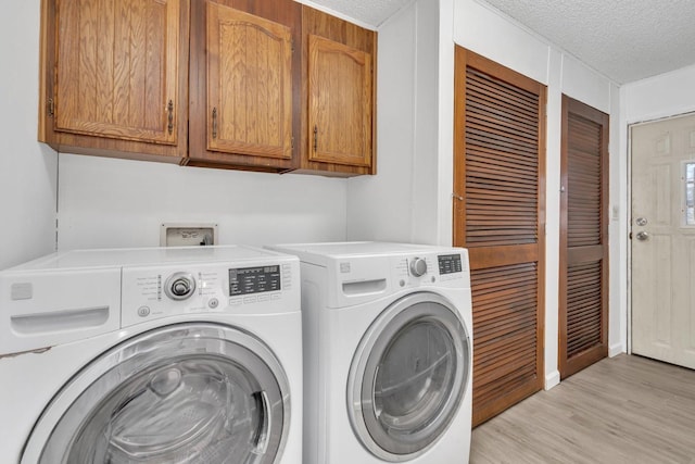 laundry area featuring cabinets, washer and dryer, a textured ceiling, and light hardwood / wood-style floors