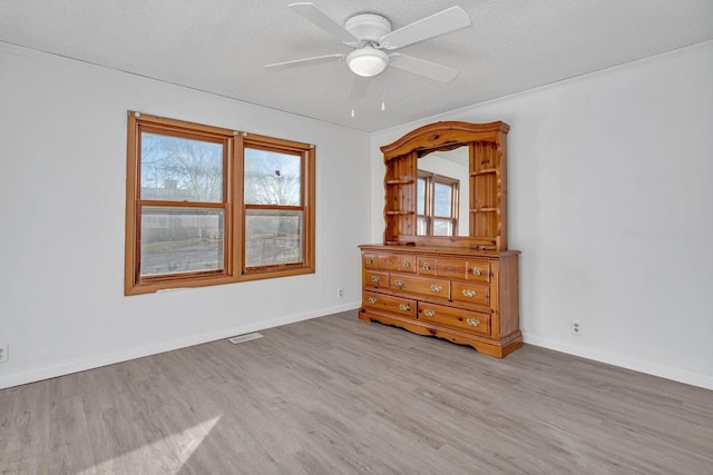 unfurnished room featuring ceiling fan, light hardwood / wood-style flooring, and a textured ceiling