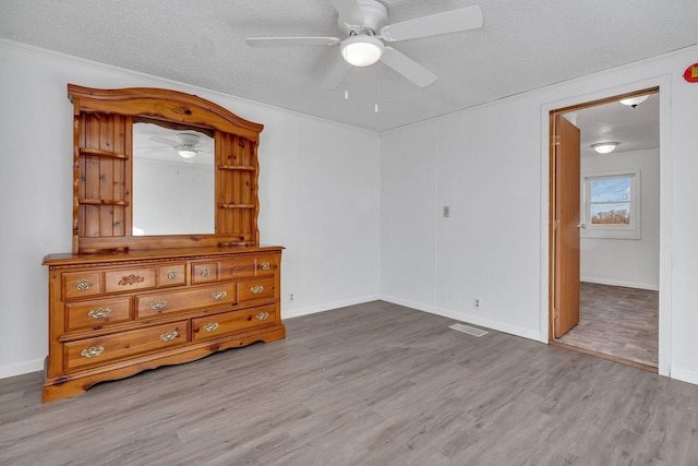 unfurnished bedroom featuring ceiling fan, wood-type flooring, and a textured ceiling