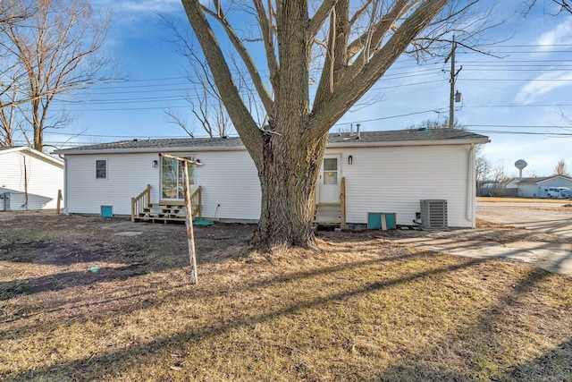 rear view of property with cooling unit and a yard