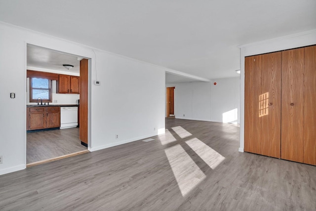 unfurnished living room featuring sink and light hardwood / wood-style flooring