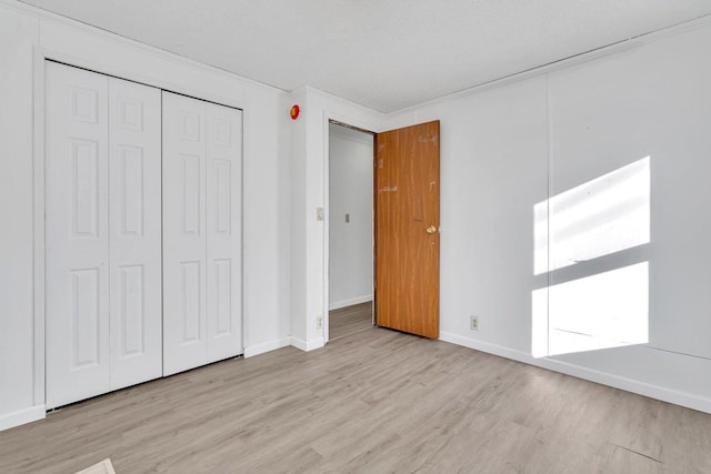 unfurnished bedroom with a closet, light hardwood / wood-style flooring, and a textured ceiling