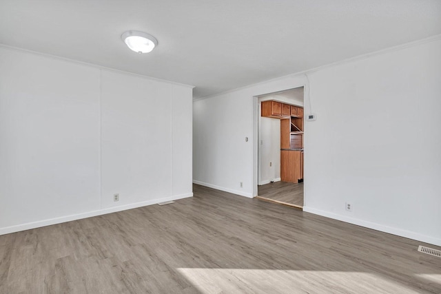 spare room featuring hardwood / wood-style floors and ornamental molding