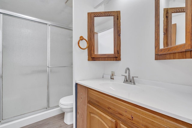 bathroom with a shower with door, vanity, hardwood / wood-style flooring, and toilet